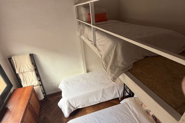 Perspectiva que destaca la cama superior tipo loft y las camas ubicadas junto a la ventana. La altura del ambiente aporta una sensación de mayor espacio y una experiencia diferente para descansar.