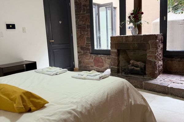 Dormitorio con cama matrimonial, decoración cálida y chimenea de piedra. Un espacio amplio y tranquilo para relajarse, con luz natural y detalles que lo hacen especial.