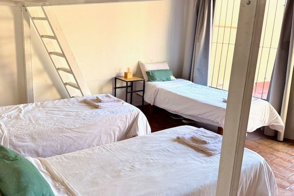 Habitación amplia y luminosa con tres camas individuales en planta baja y una cama en entrepiso. Su acceso directo a la terraza aporta luz natural y un ambiente fresco y agradable.