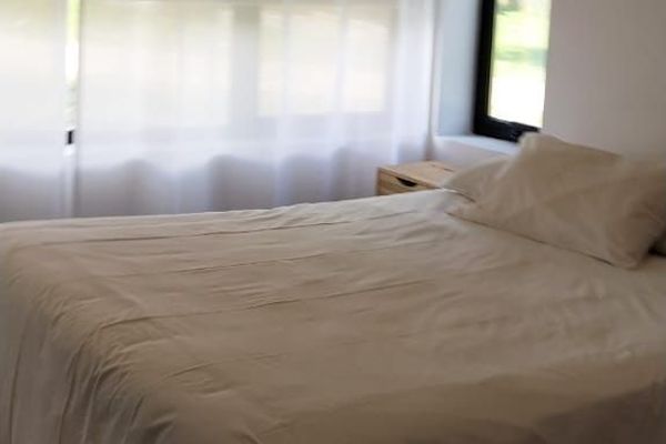 Cama queen con cortinas blackout: Cama queen con cortinas blackout y ventanal, combinando confort, privacidad y vistas a la naturaleza