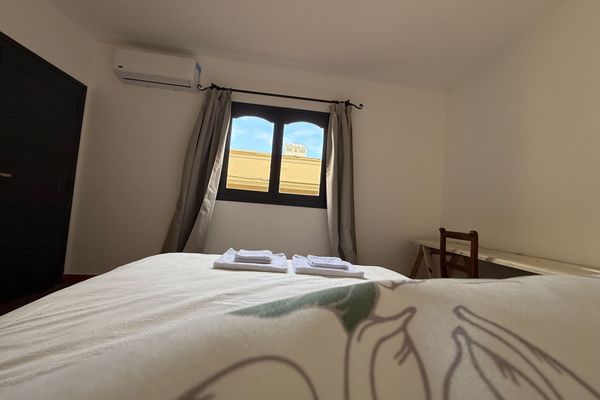 Dormitorio con cama queen, aire acondicionado y luz natural. Ideal para descansar en un ambiente simple y cómodo.