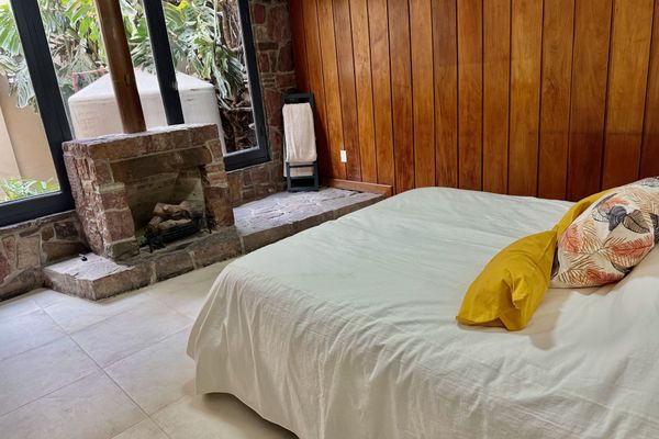 Dormitorio con cama matrimonial, decoración cálida y chimenea de piedra. Un espacio amplio y tranquilo para relajarse, con luz natural y detalles que lo hacen especial.