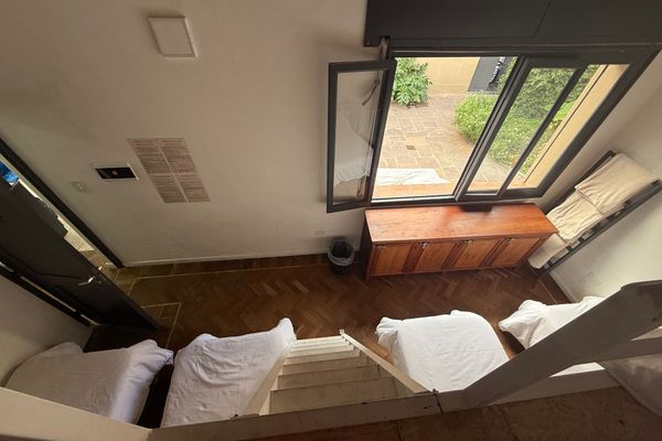Vista superior que permite apreciar la amplitud del ambiente, el acceso al entrepiso, las camas y la gran ventana con vista al jardín interior, proporcionando un espacio luminoso y agradable.