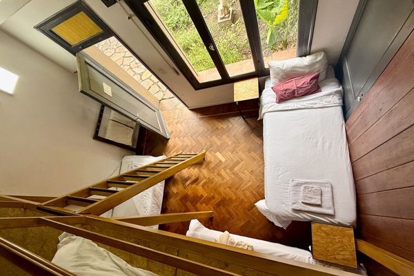 Vista lateral de la cama superior, equipada con ropa de cama y baranda de seguridad. Un rincón cómodo que aprovecha al máximo la altura del ambiente.