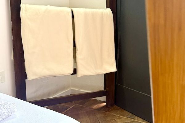 Un ambiente cálido y acogedor con pisos de madera, ropa de cama blanca y detalles cuidadosamente preparados para una estadía confortable.